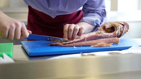 personal de la cocina cortando un pescado abierto y preparándolo en el restaurante