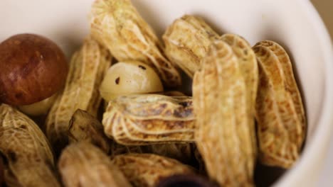 peanuts and nuts arranged in a white bowl