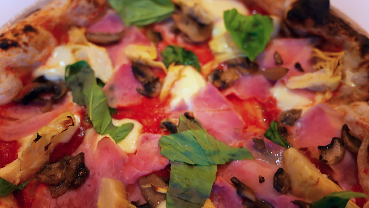 Close up of pizza with artichoke, ham, mushrooms and basil