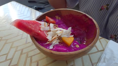 girl eating healthy dragon fruit acai bowl, delicious smoothie bowl, filmed in bali indonesia