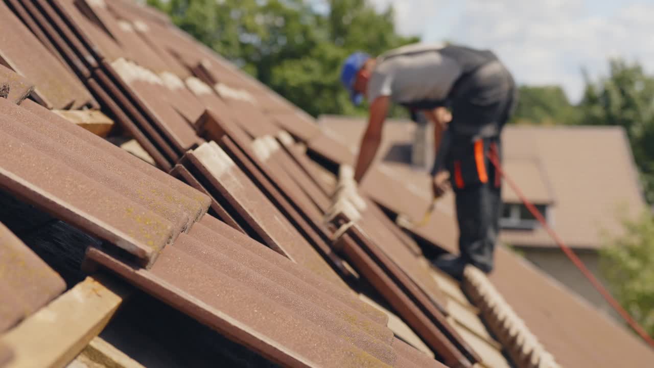 Tettoista che posa tegole su un tetto di casa.