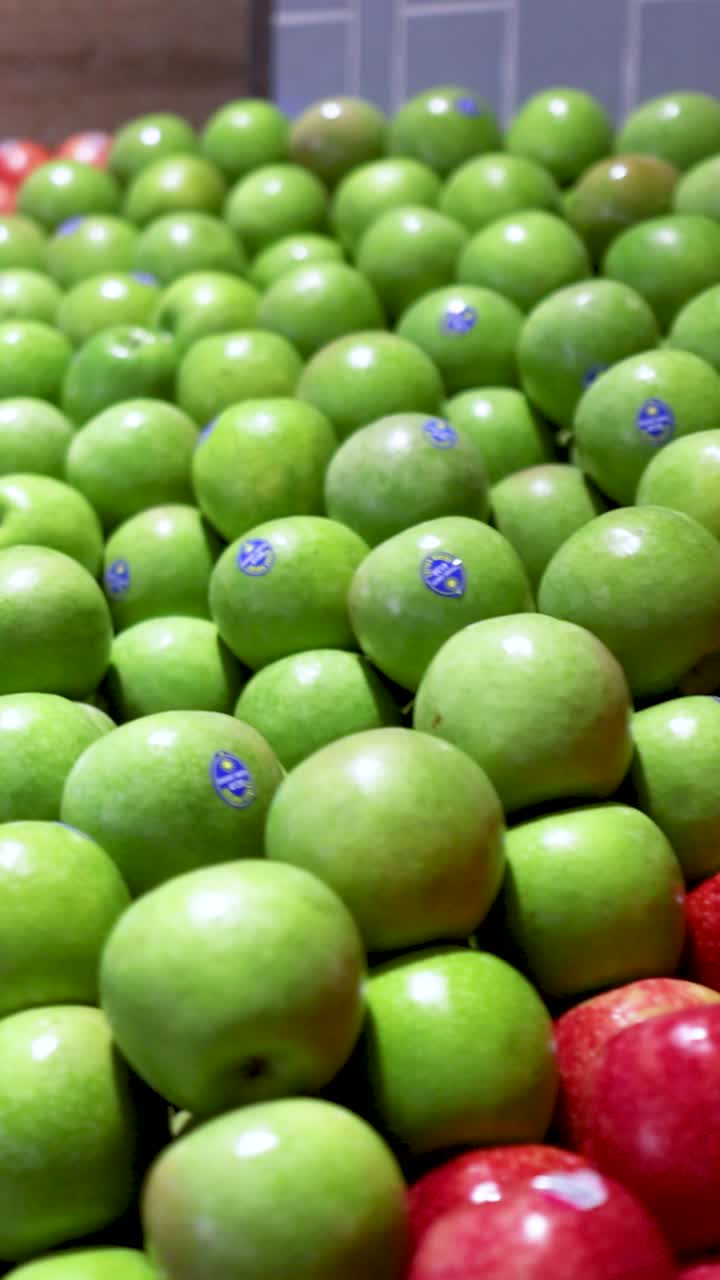 Een dynamische close-up van rode en groene appels in een supermarkt, met levendige kleuren en een verse productpresentatie