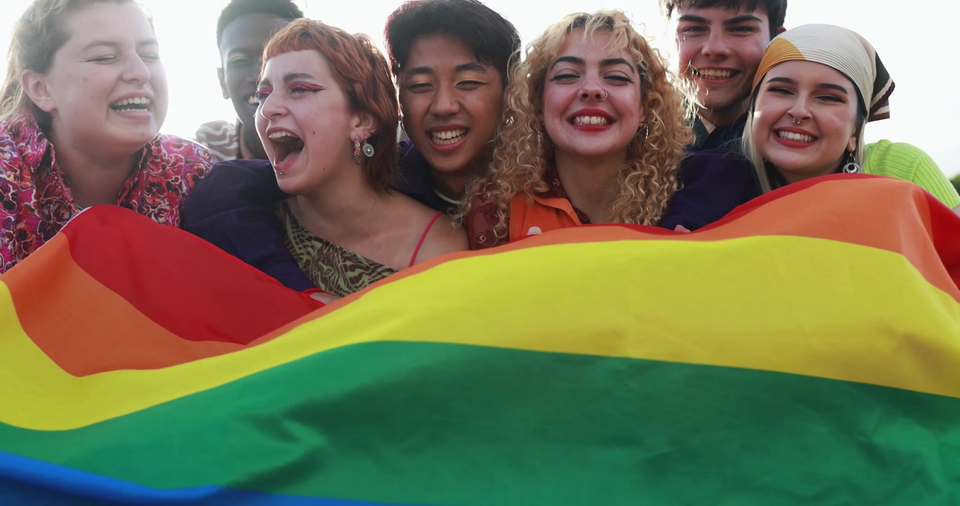 Jovens Diversos Felizes Segurando Bandeira Arco-Íris e Sorrindo