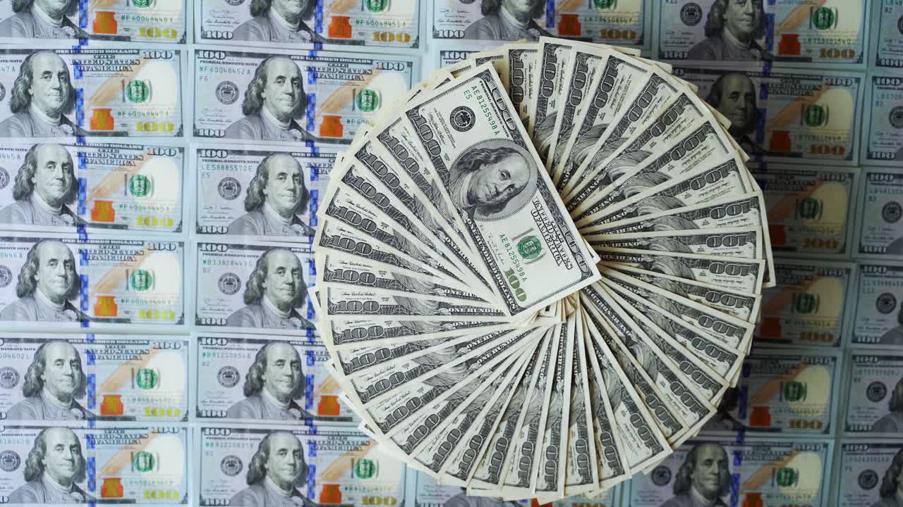 Dollar banknotes background. Hundred american dollars bills rotating in a circle way among colorful money. Financial background. Selective focus.