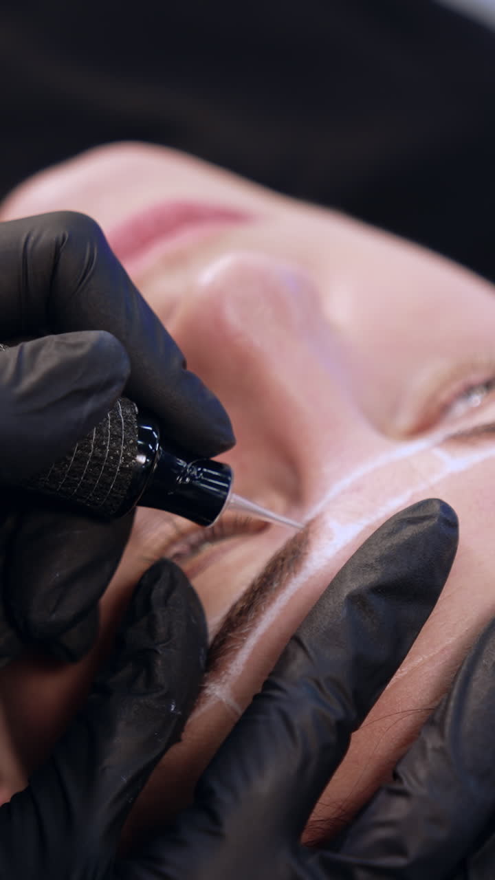 Permanent make up instrument held in the gloved hand of a brow master. Cosmetology and beauty concept. Vertical video