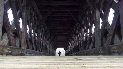 Niedriger-Weitwinkel-Auf-Fußgänger,-Der-Am-Ende-Der-überdachten-Brücke-In-Sicht-Kommt-Und-Auf-Die-Kamera-Zugeht,-Zeigt-Holzdesign-Im-Innenbereich