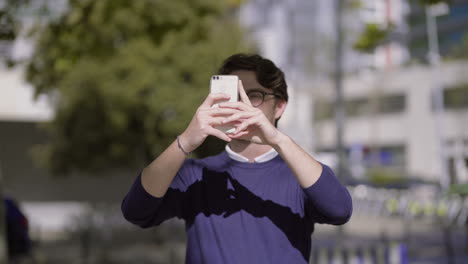 Man-in-eyeglasses-taking-pictures-with-smartphone-outdoor