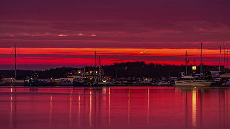 luxury boats and cityscape during red sunset sky, time lapse view