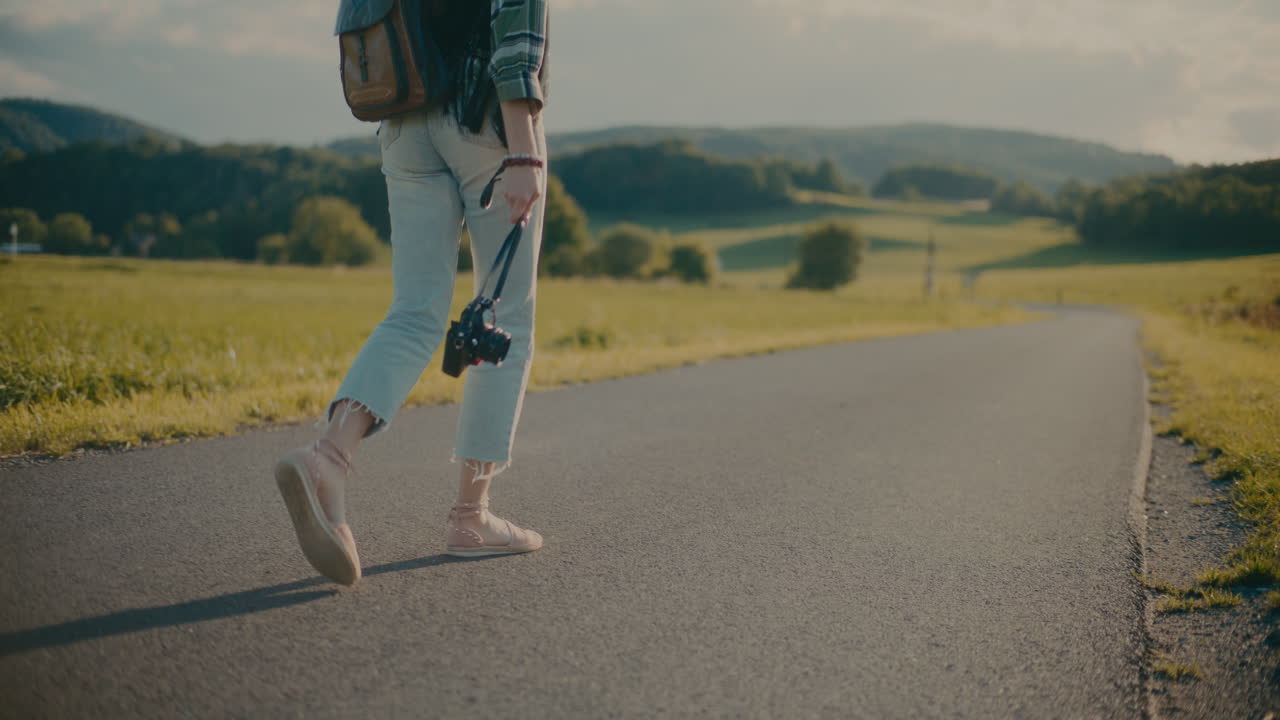 Woman Holding Camera While Walking On Road