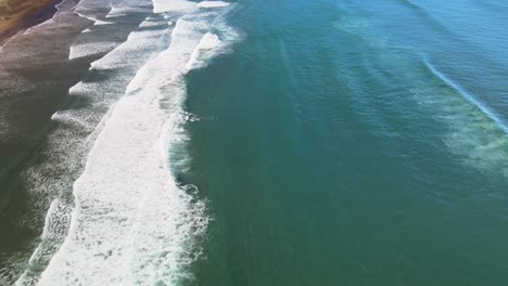 inclinación aérea de la playa de arena negra y las olas