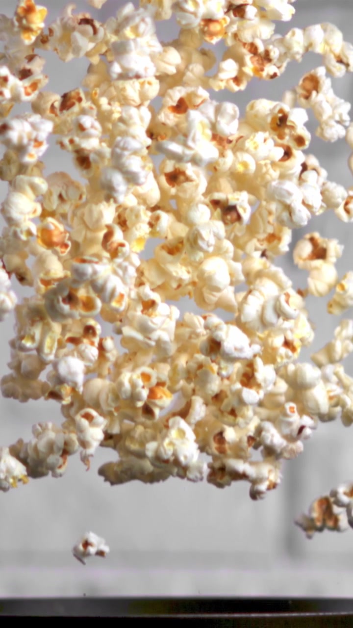 Popcorn appena scoppiati che cadono al rallentatore da una padella