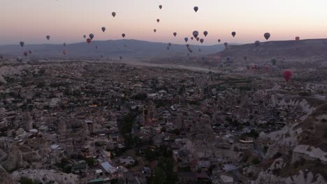 panorámica de camiones aéreos sobre las formaciones rocosas únicas y los extensos valles de capadocia, turquía, bajo cielos despejados al amanecer con globos de aire caliente a través del cielo suave