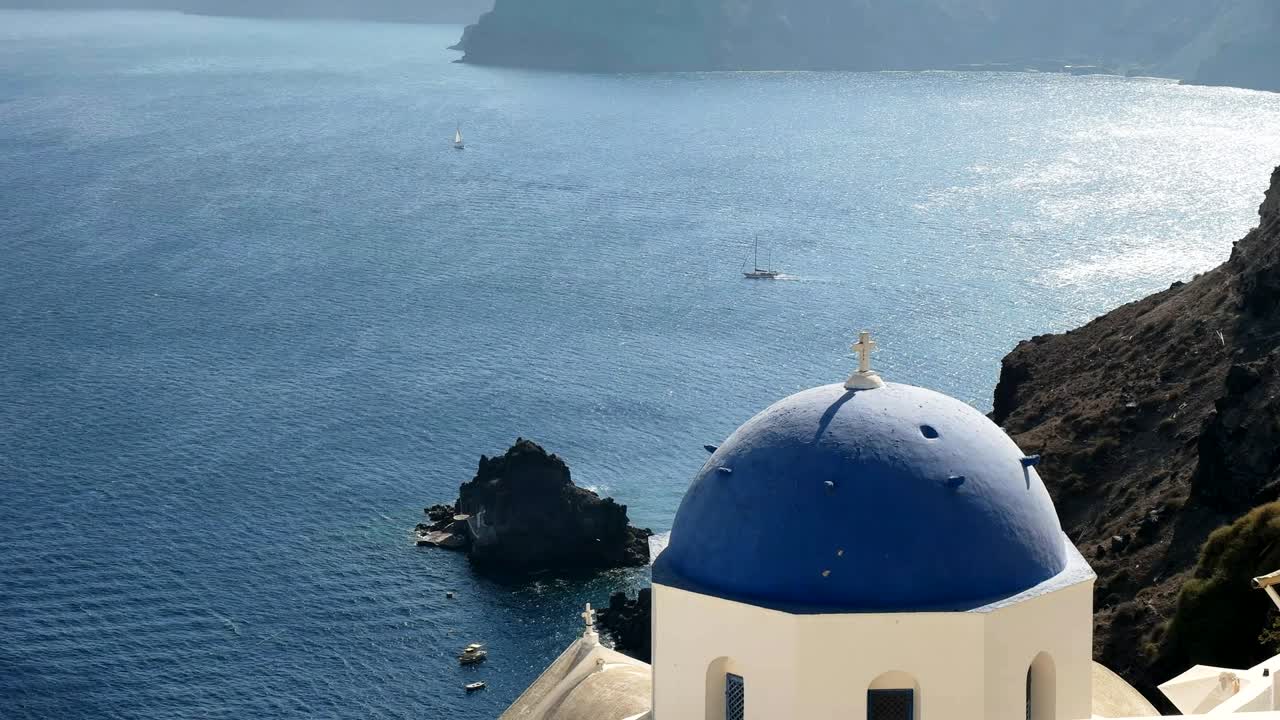 blue domed church with a yacht in the background at oia, santorini