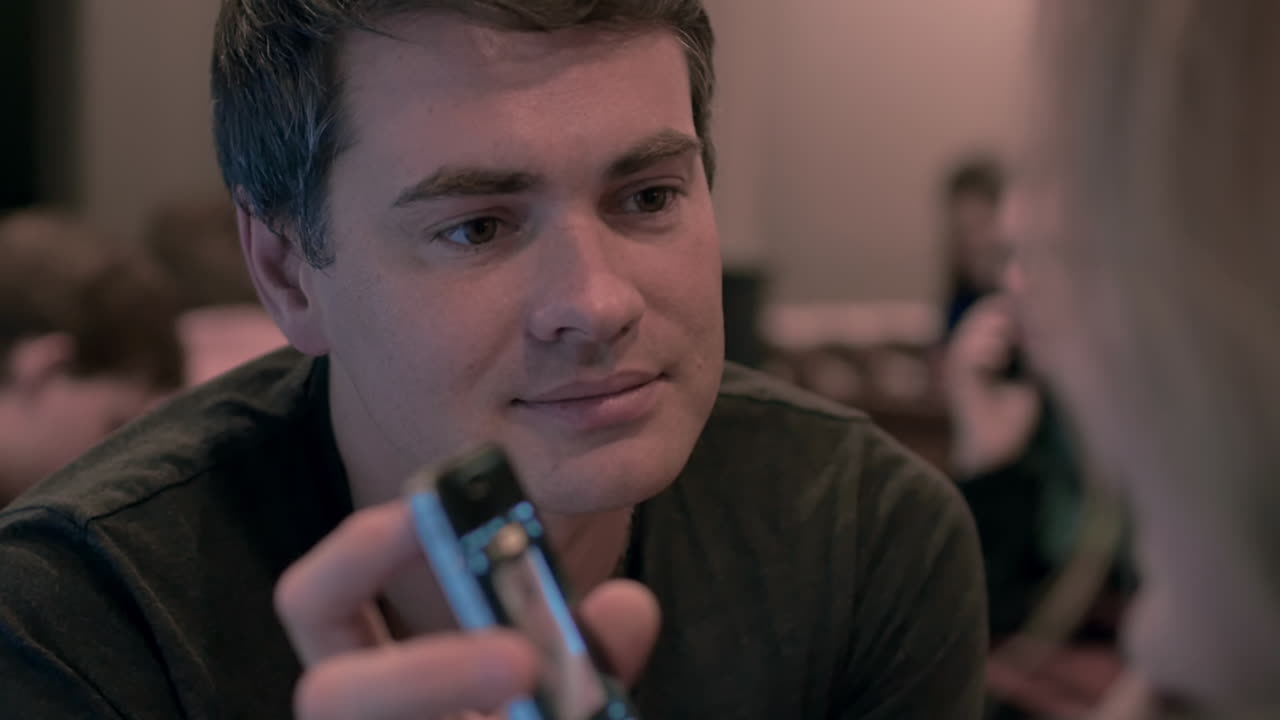 hombre con teléfono celular mostrando video a la mujer