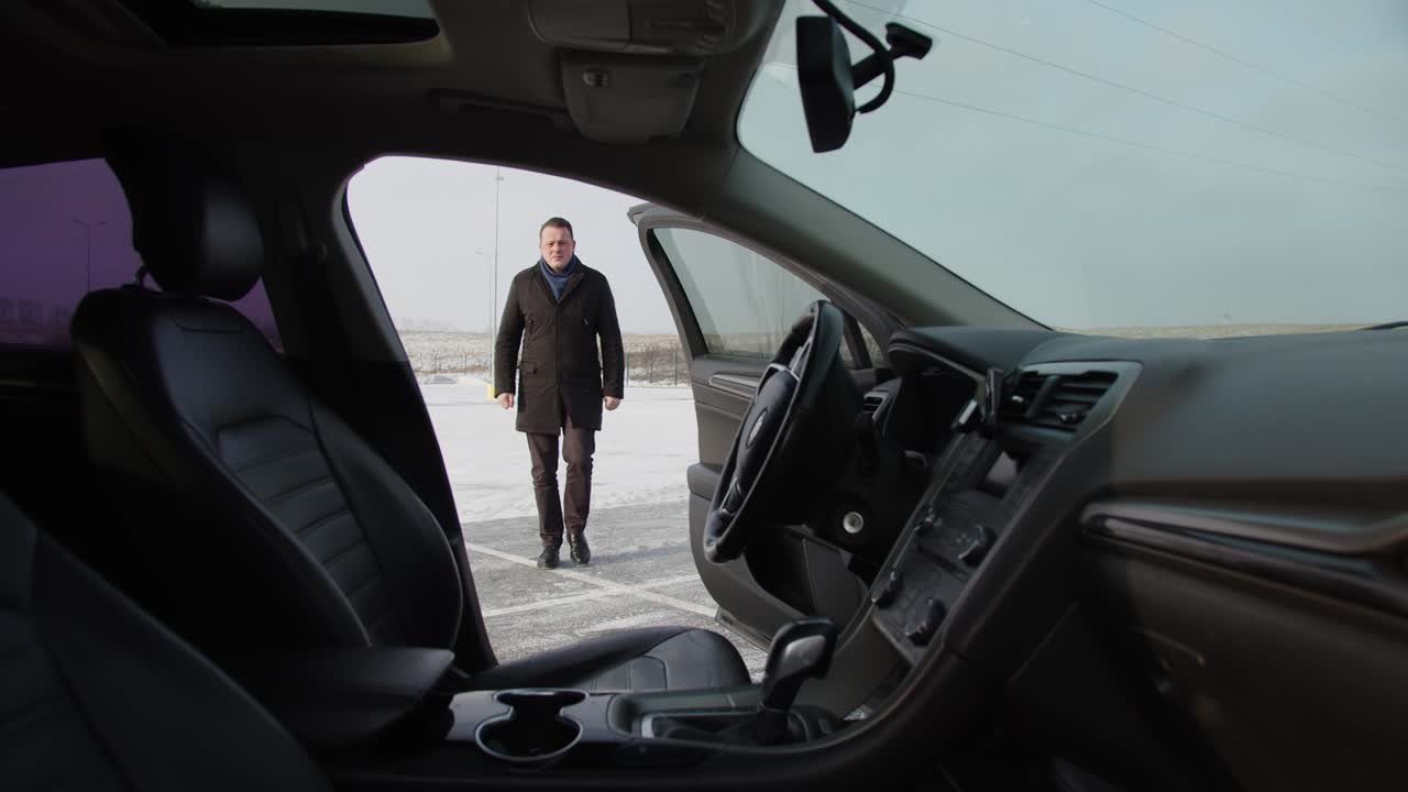 Liikemies menee autolleen ja istuu ratin taakse.
