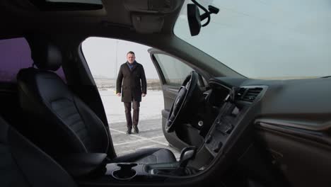 el hombre de negocios va a su coche y se pone al volante.
