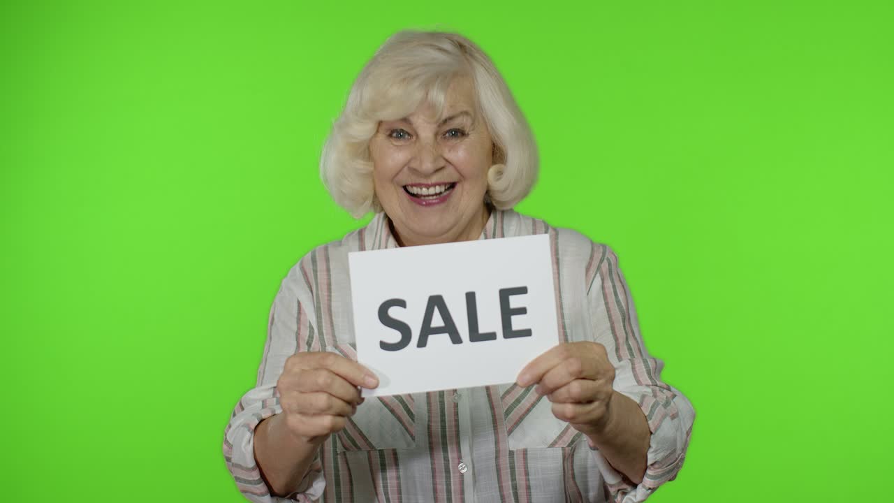 Ældre stilfuld bedstemor smiler og holder et banner med ordet "Udsalg". Black Friday