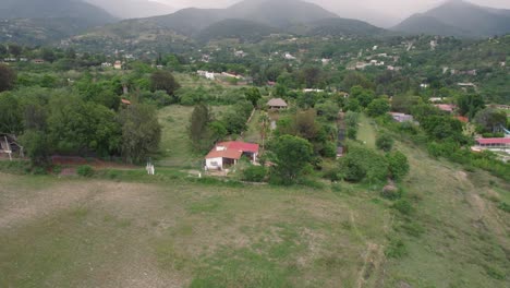 Soaring-above,-witness-an-eco-friendly-house-enveloped-by-lush,-green-trees-in-the-heart-of-nature