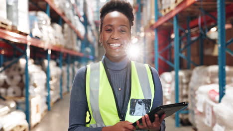 a black woman in a warehouse smiling and holding a tablet