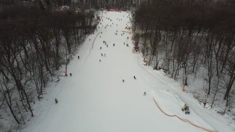 Skifahrer-Und-Snowboarder-Fahren-Am-Wochenende-Auf-Schneepisten-Mit-Skilift.-Drohne-Fliegt-An-Einem-Frostigen-Wintertag-Mit-Skifahrern-Und-Snowboardern-über-Verschneiten-Hang-Im-Skigebiet:-Drohnenansicht