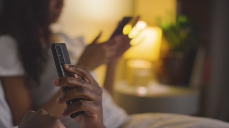 Primo piano di coppia con problemi di relazione a casa di notte, entrambi che guardano i telefoni cellulari in camera da letto 11
