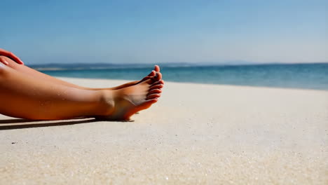 person's feet relaxing on a sunny beach