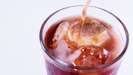 coca cola is poured into a glass from a bottle