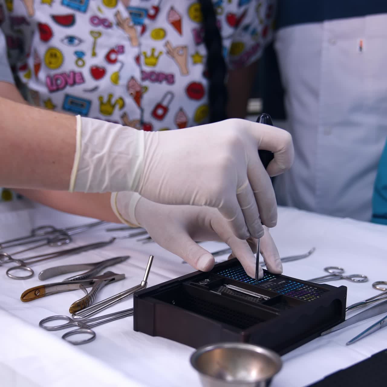 Gloved hands of a teacher holding a screwdriver and pulling the tiny screw. Dentistry students are taught at practice. Close up