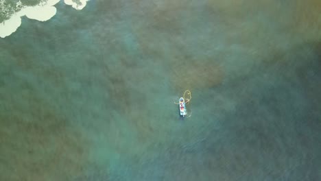vista aérea de arriba hacia abajo de un pequeño barco de pesca y una red en el agua verde del océano por la costa de iquique, chile, ángulo alto