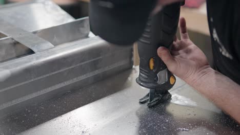 close-up of man worker sawing metal peace of frame with reciprocating saw