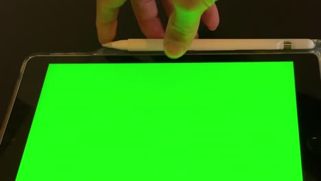 man looking at tablet with green screen