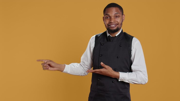Waiter in professional uniform pointing at something to the left or right
