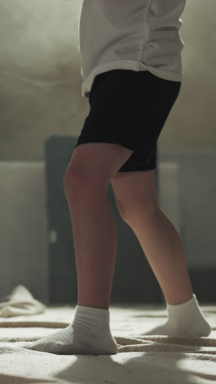 Kid kicks pad on trainer hand in martial arts gym. Skilled trainer and toddler boy study hits by legs in combat center slow motion. Kickboxing fight