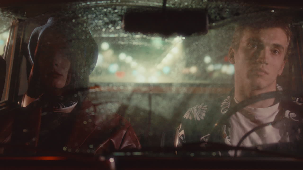 Young Couple Sitting Inside Retro Car during Rainy Night Drive