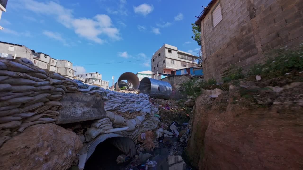 Ripresa FPV che vola attraverso Cañada de Guajimía, mostrando rifiuti e tubi per un nuovo sistema di drenaggio in costruzione