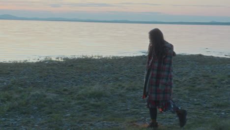 young woman with lantern wandering around lake shore at dusk