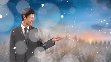 animation of snow falling over hands of caucasian businessman and winter landscape