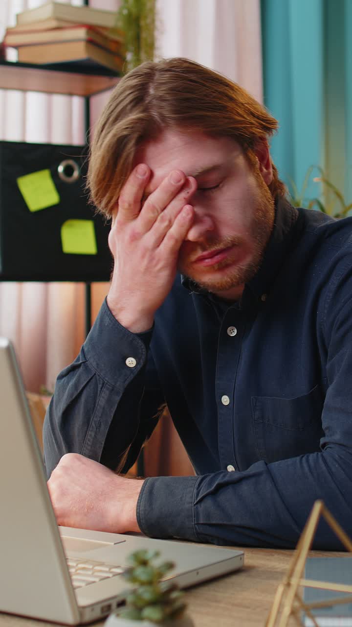 Impiegato annoiato e assonnato che lavora al computer portatile, sbadiglia, si appoggia alla mano e si addormenta in ufficio