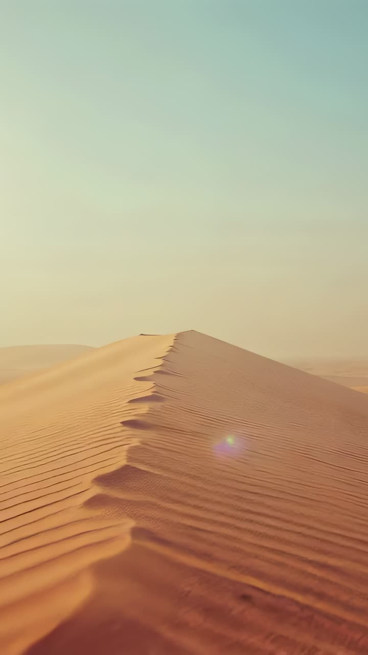 Video verticale: la telecamera inizia a spingere la cresta di una duna nel deserto, rivelando increspature con riverbero del sole