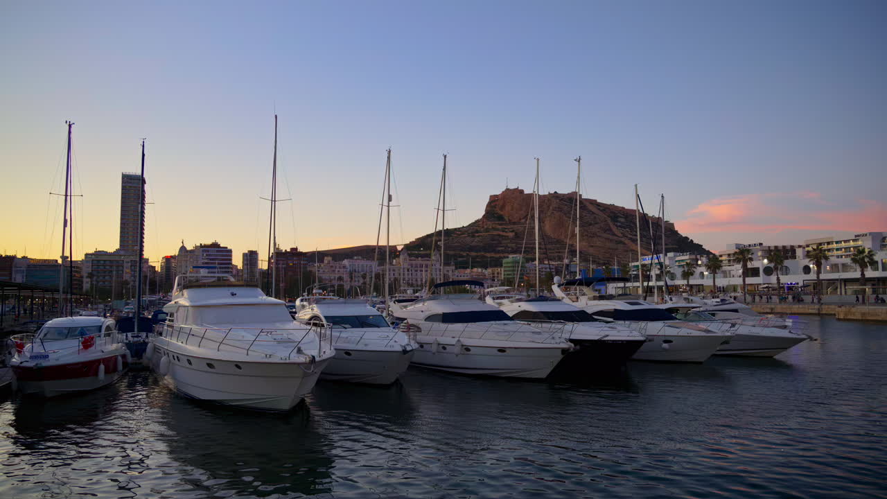 Alicante, Spain - May 22, 2025: Multiple boats docked in the Alicante marina overlooking the castle at sunset
