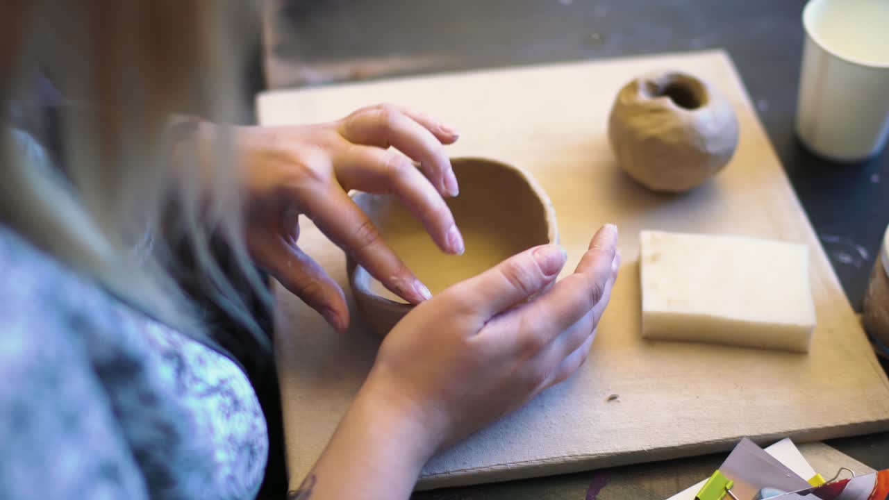 manos de una joven elaborando un cuenco con arcilla en un taller de cerámica