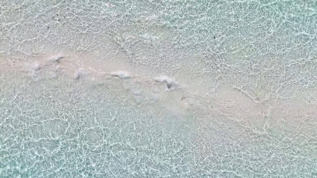 Aerial view of shallow, crystal clear waters gently rippling over Candaraman Sand Bar in Balabac, Palawan, Philippines, revealing the sandy textures beneath the surface in a tranquil tropical setting