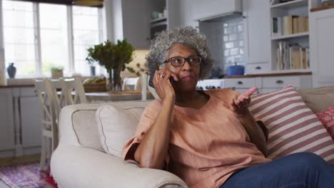 senior african american woman talking on smartphone while sitting on the couch at home