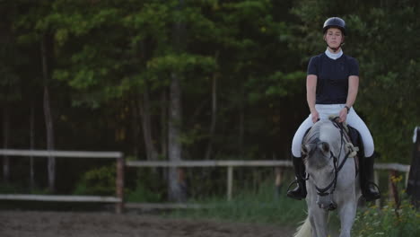 slow motion close up. a female jockey is riding a horse. a female jockey is riding a horse in a corral