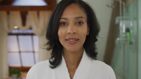 Portrait-of-mixed-race-woman-wearing-bathrobe-looking-at-camera-and-smiling