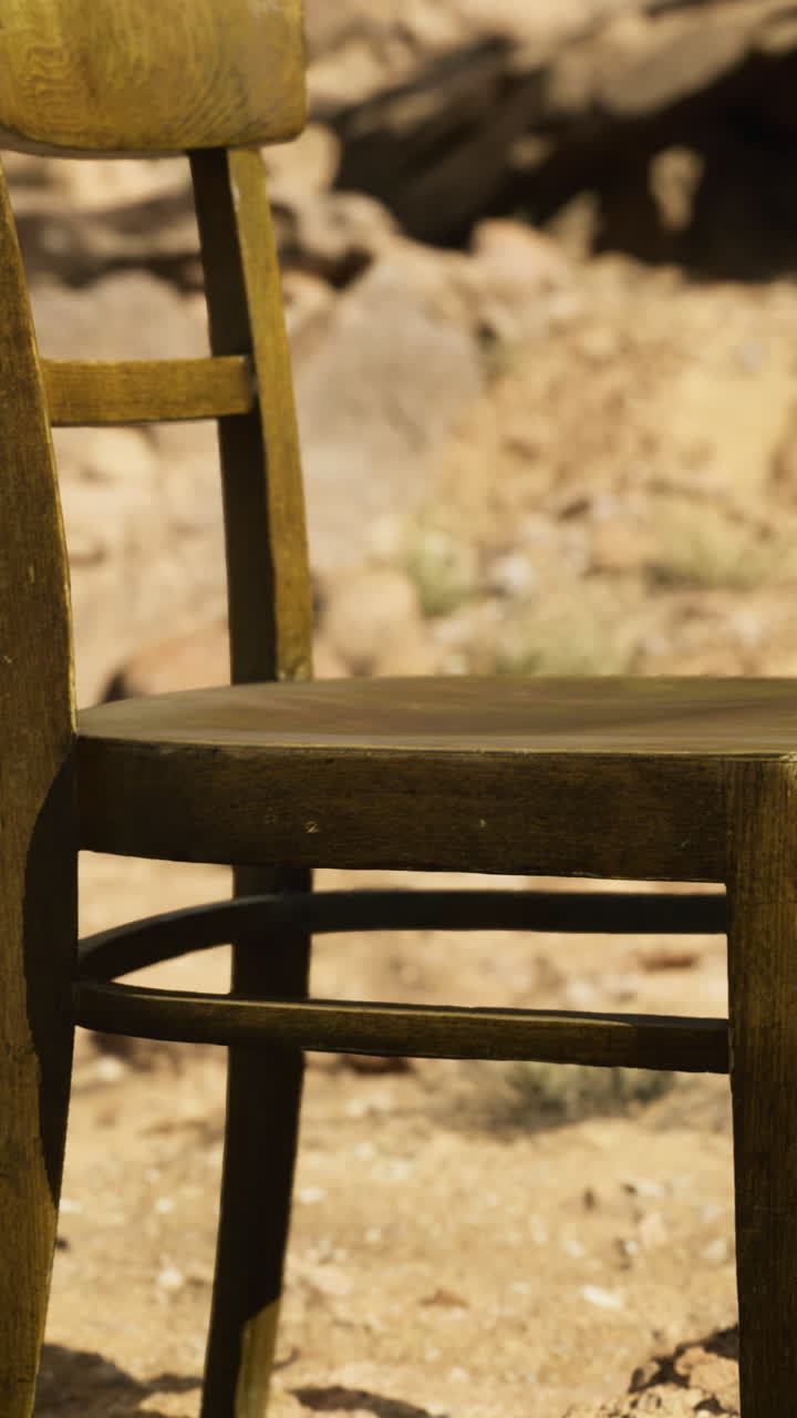 Unique wooden chair placed on sandy desert terrain under bright sunlight