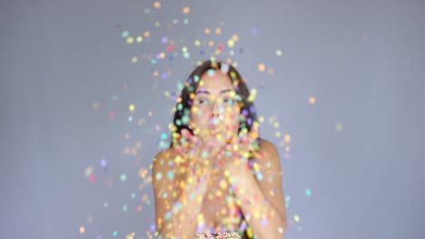 Young-woman-blowing-colorful-New-Year-confetti