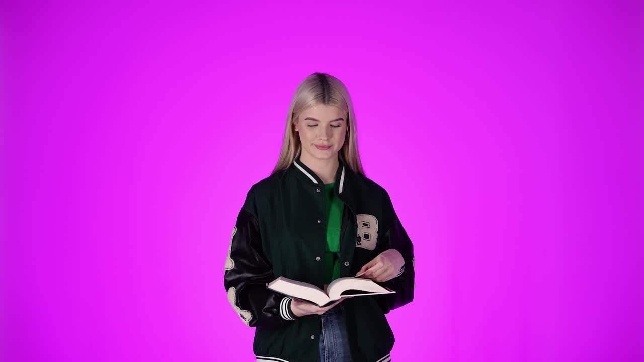 Giovane donna felice legge un libro comico, ridendo e sorridendo, scatto in studio