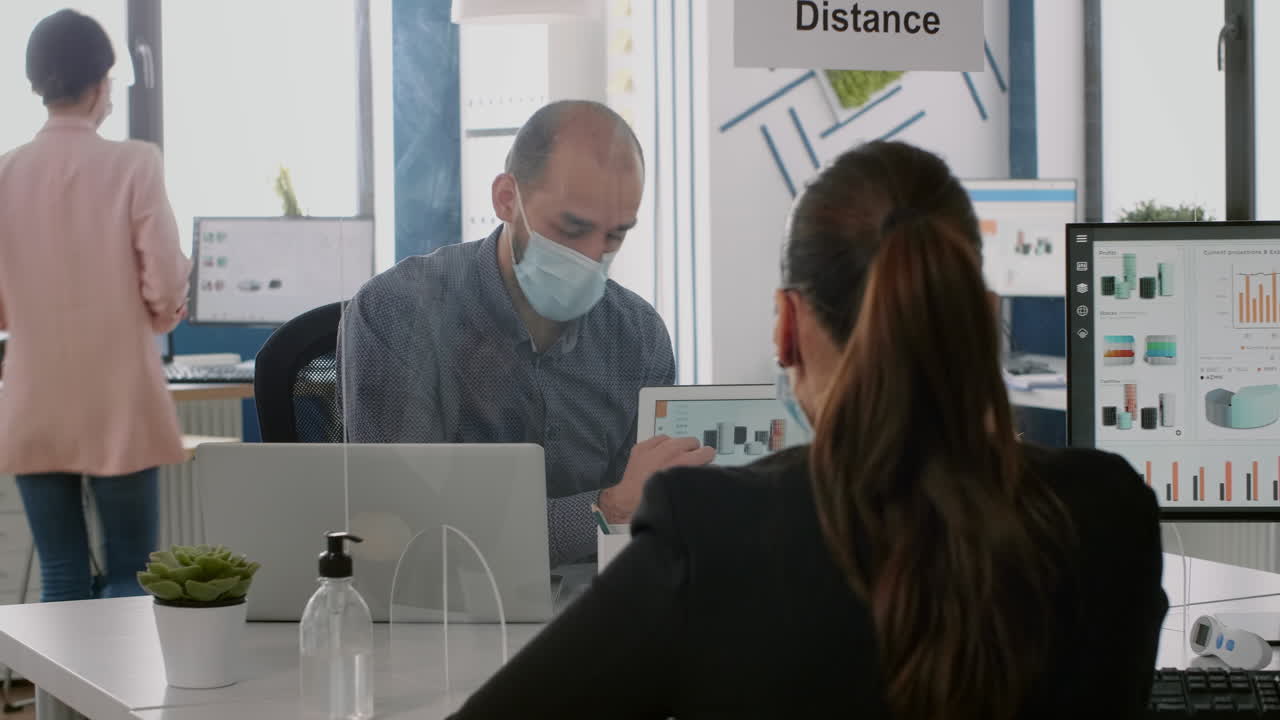 compañeros de trabajo con máscaras protectoras hablando de estadísticas de gestión