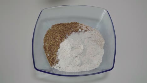 sprinkling pinch of salt into flour baking mixture in glass bowl, overhead